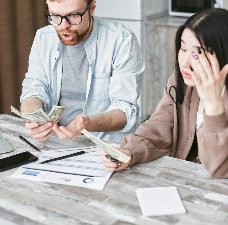 A man and woman hold money while a bill sits on the table.