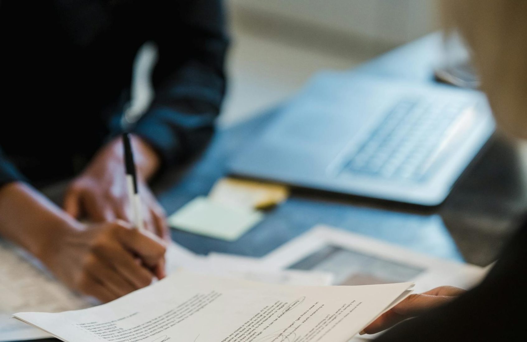 pexels-mizunokozuki-12899103 - Associated Currency Exchanges A person filling out paperwork.