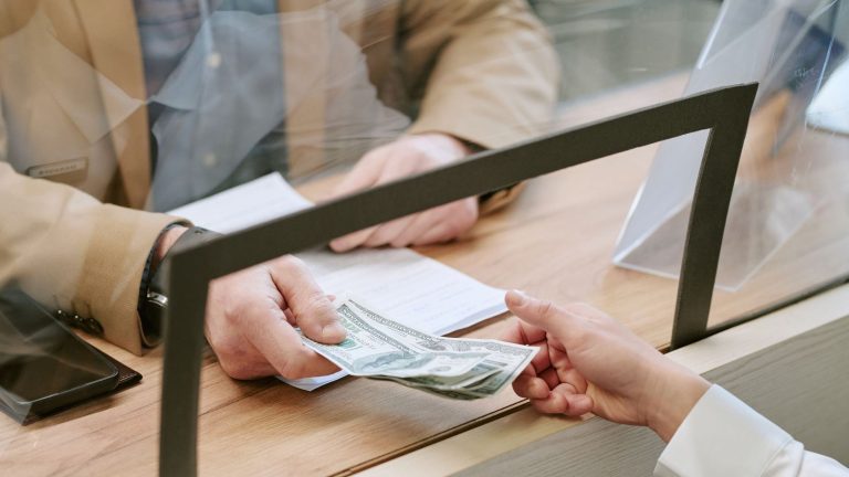 A man giving cash to a bank teller.